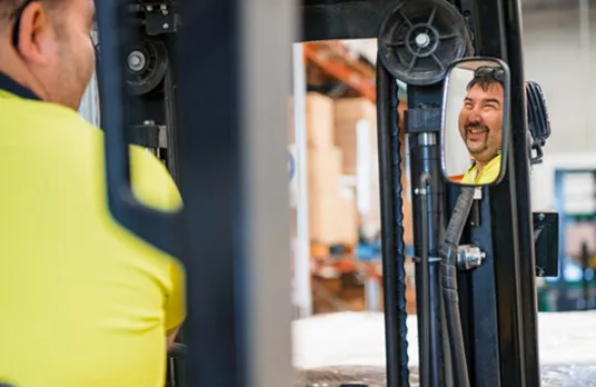 Hone supported employee smiling on forklift