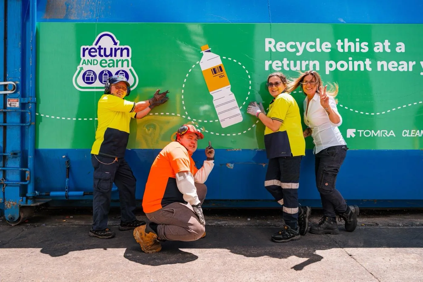 Hone Return and earn employees standing in front of the return and earn sign