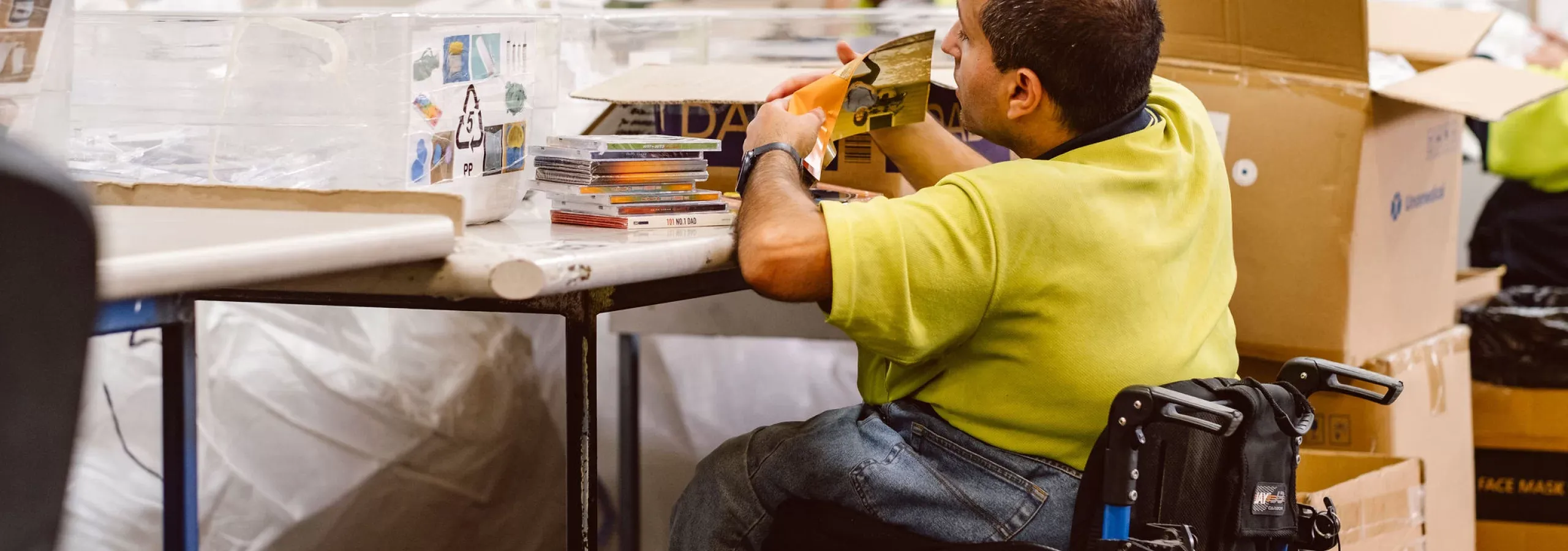 Hone supported employee working to dispose of CD waste from wheelchair
