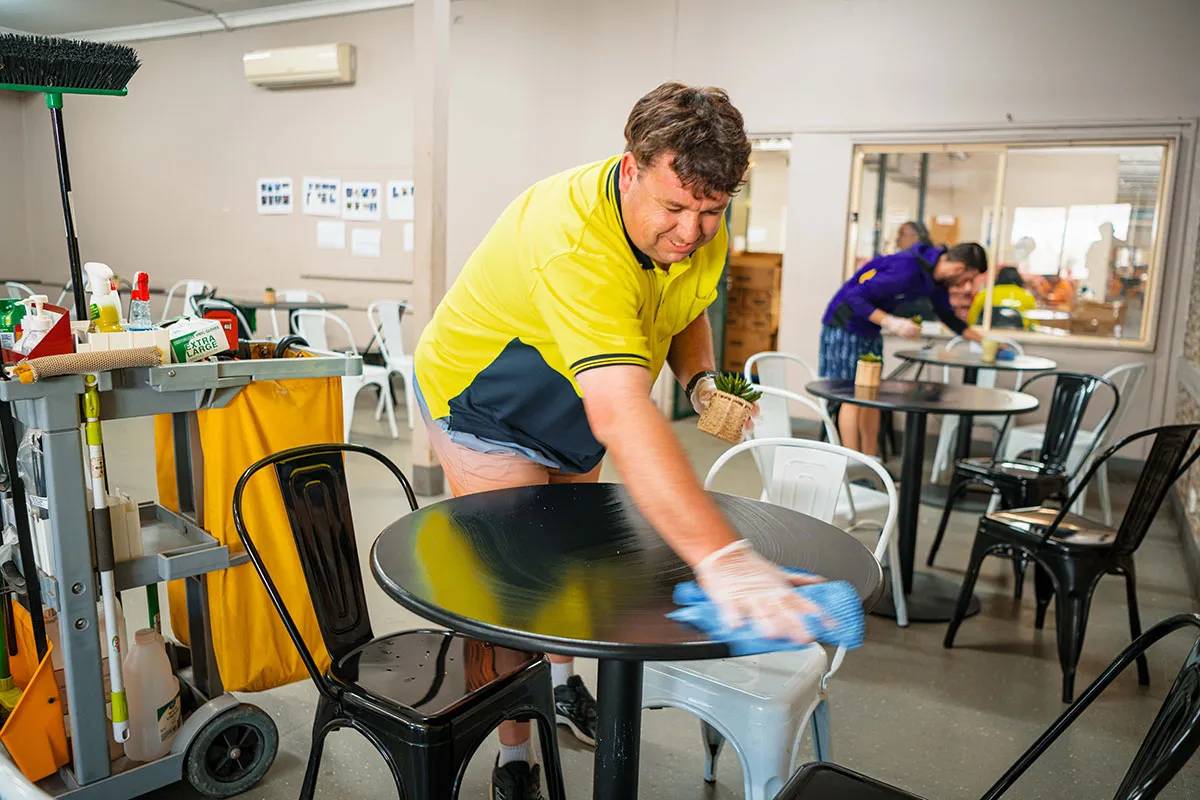 Hone supported workers cleaning tables in work sight.
