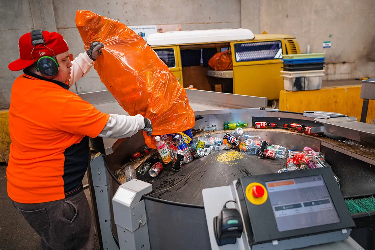 Hone supported employee emptying bag on containers onto conveyer belt