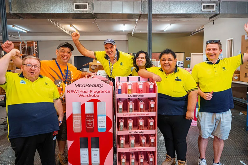 Hone supported employees in warehouse standing around retail display they just built