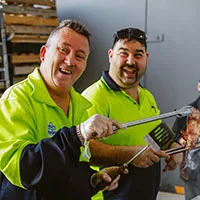 2 male Hone supported employees cooking a BBQ