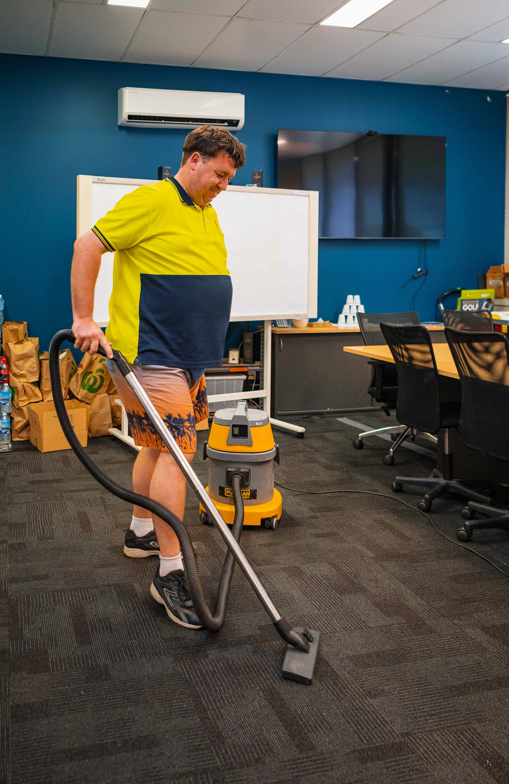 Hone supported worker vacuuming the floor in an office