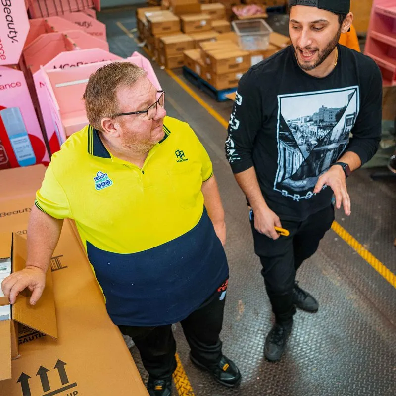 Hone supported employee in warehouse with support staff. Packing items for distribution